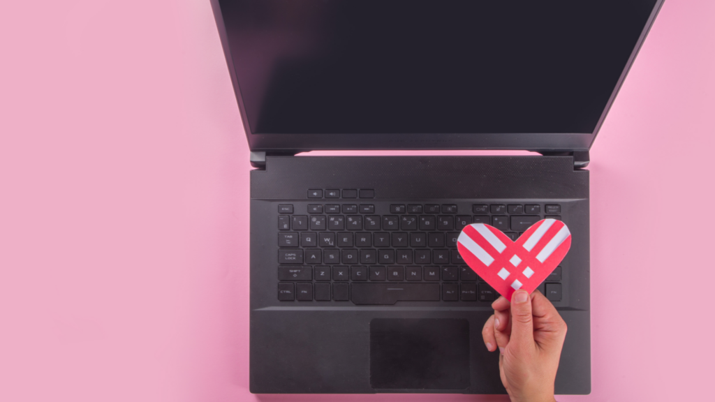 Een hartje boven een gedoneerde laptop met een roze achtergrond.